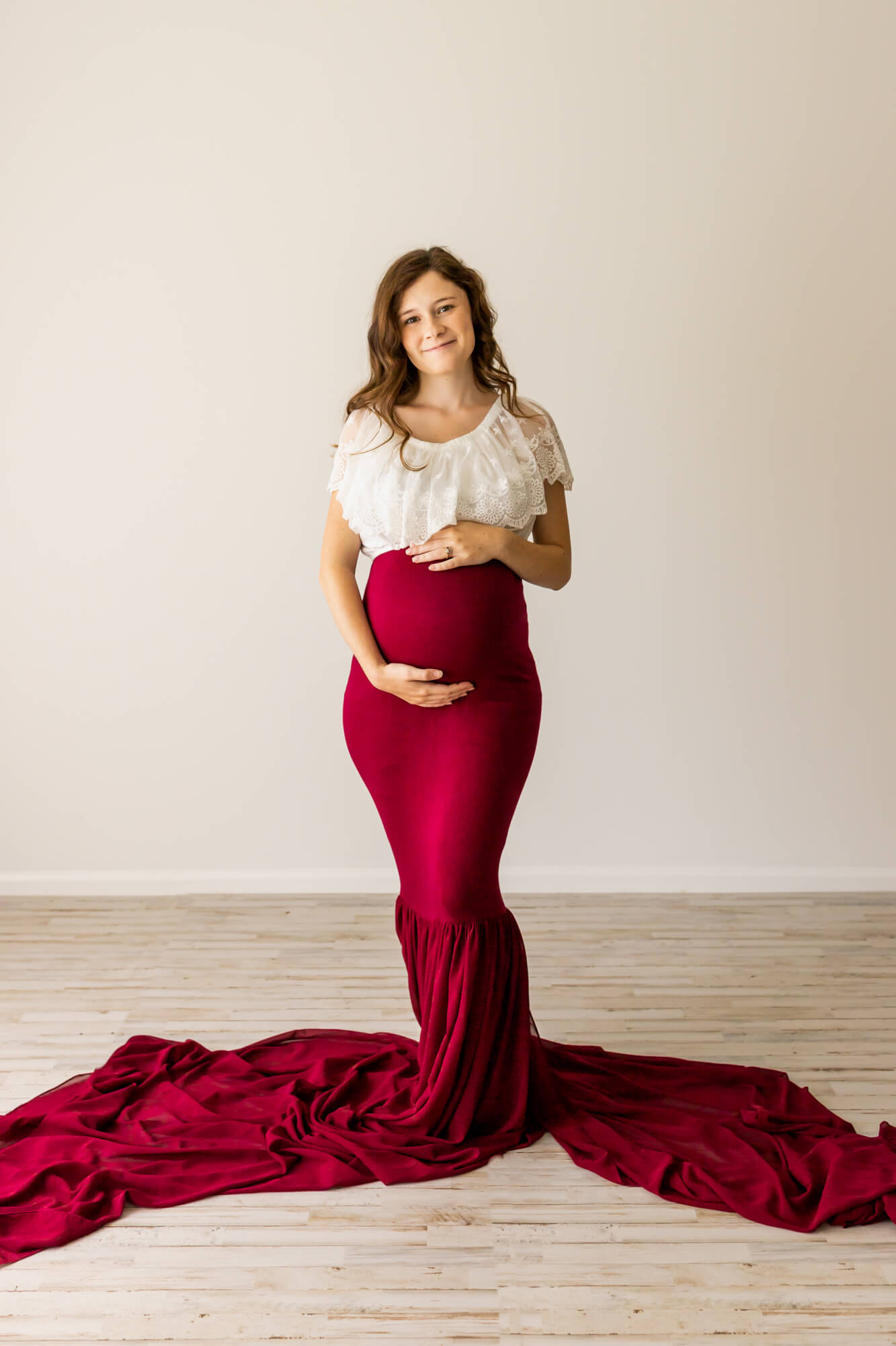 pregnant woman in white and red gown holding her bump