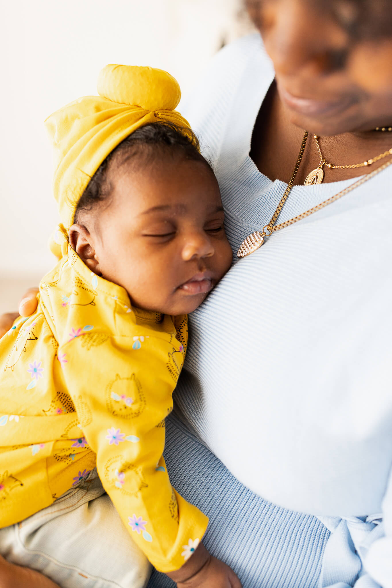 newborn baby dressed in yellow snuggling on mom