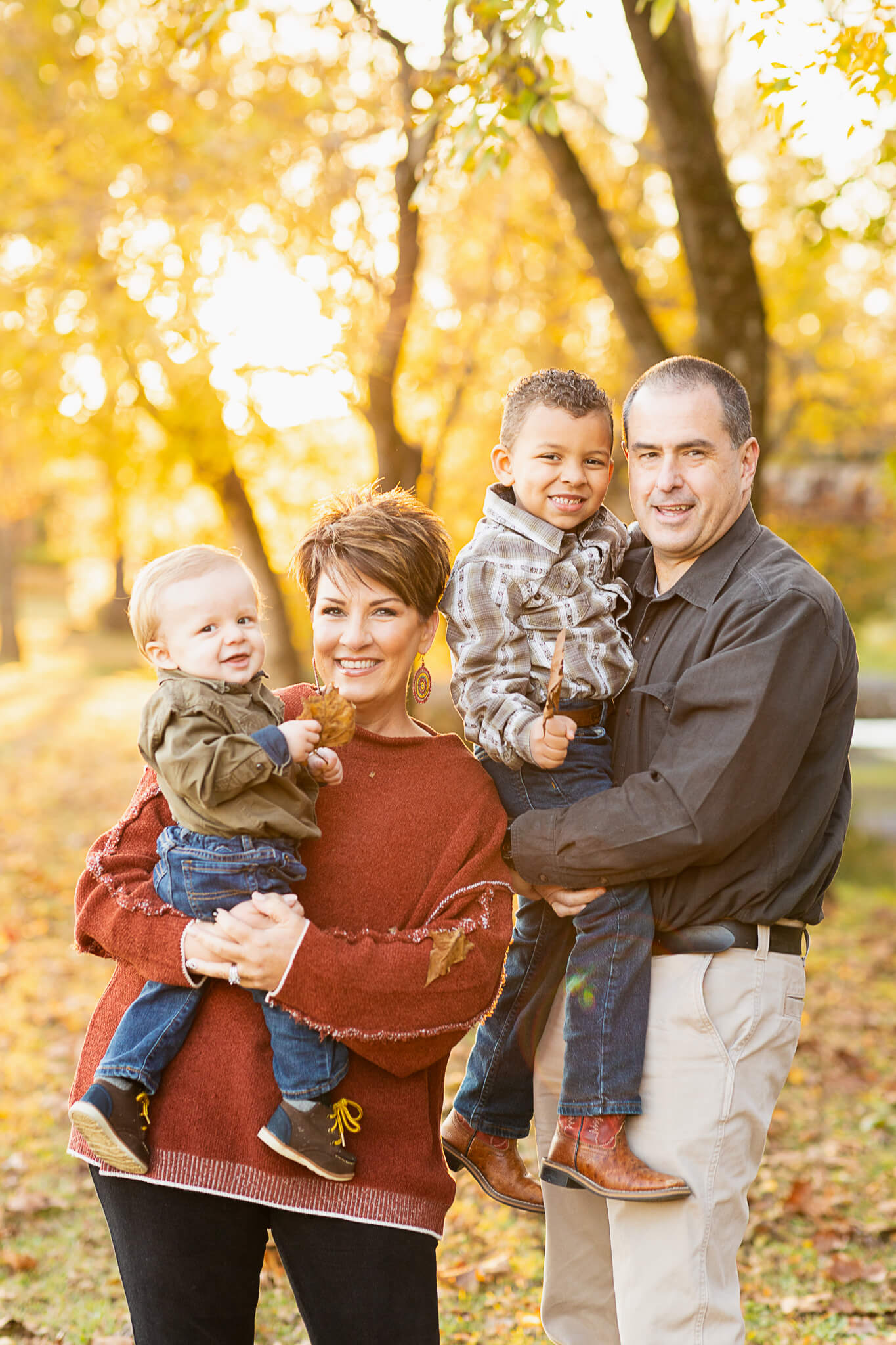 Family of four dressed in fall clothing smiling at the camera