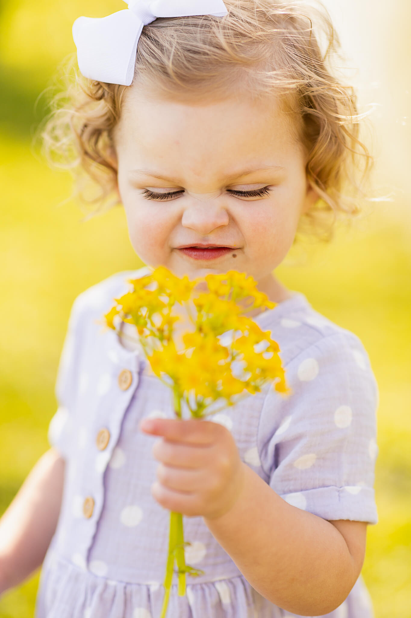 little girl in purple polka dots smelling the flowers Lawn care birmingham al
