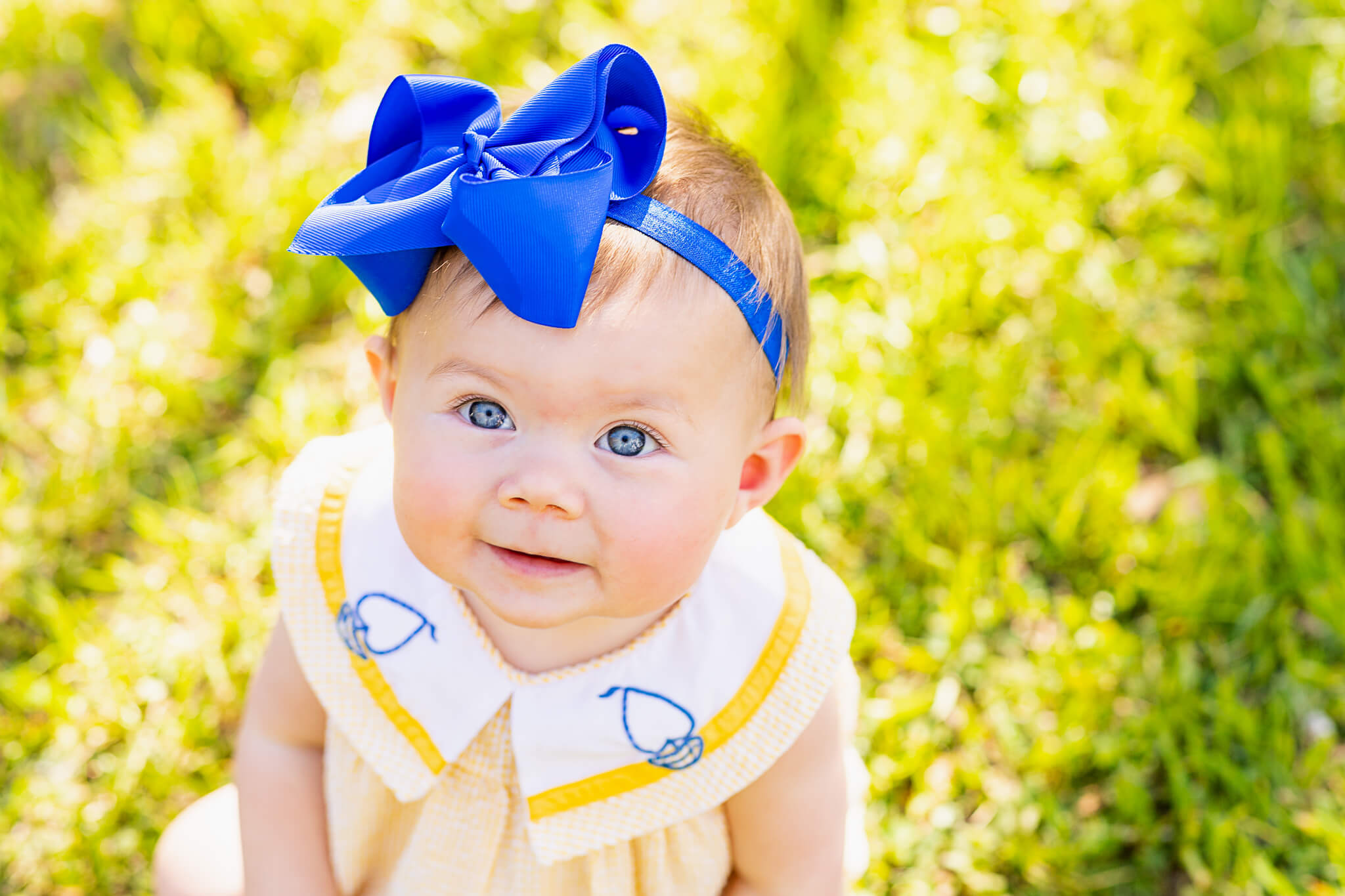 little girl in yellow dress and blue bow smiling up at the camera mommy and me classes birmingham al