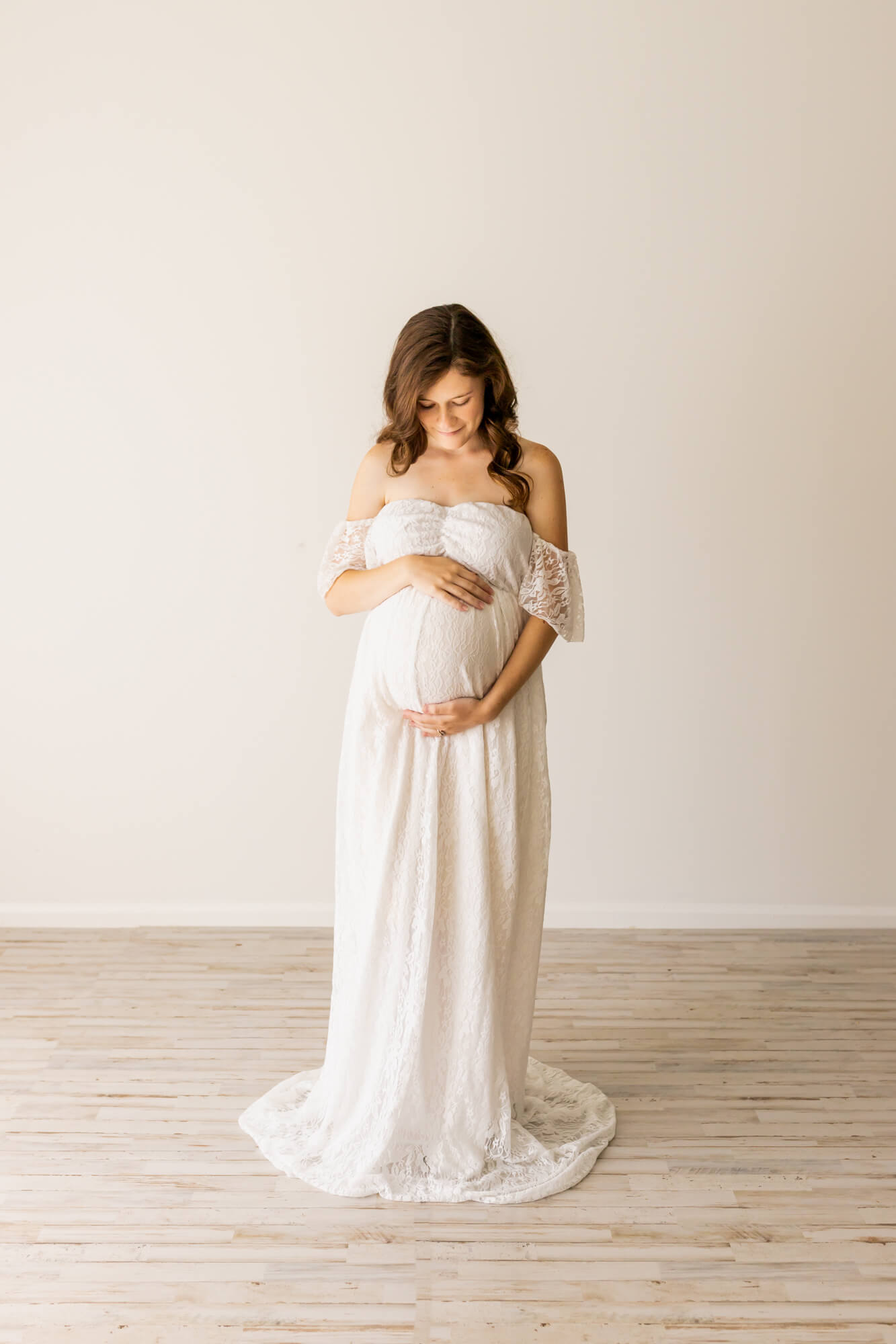 pregnant mom in white gown holding her bump and looking at it prenatal yoga birmingham