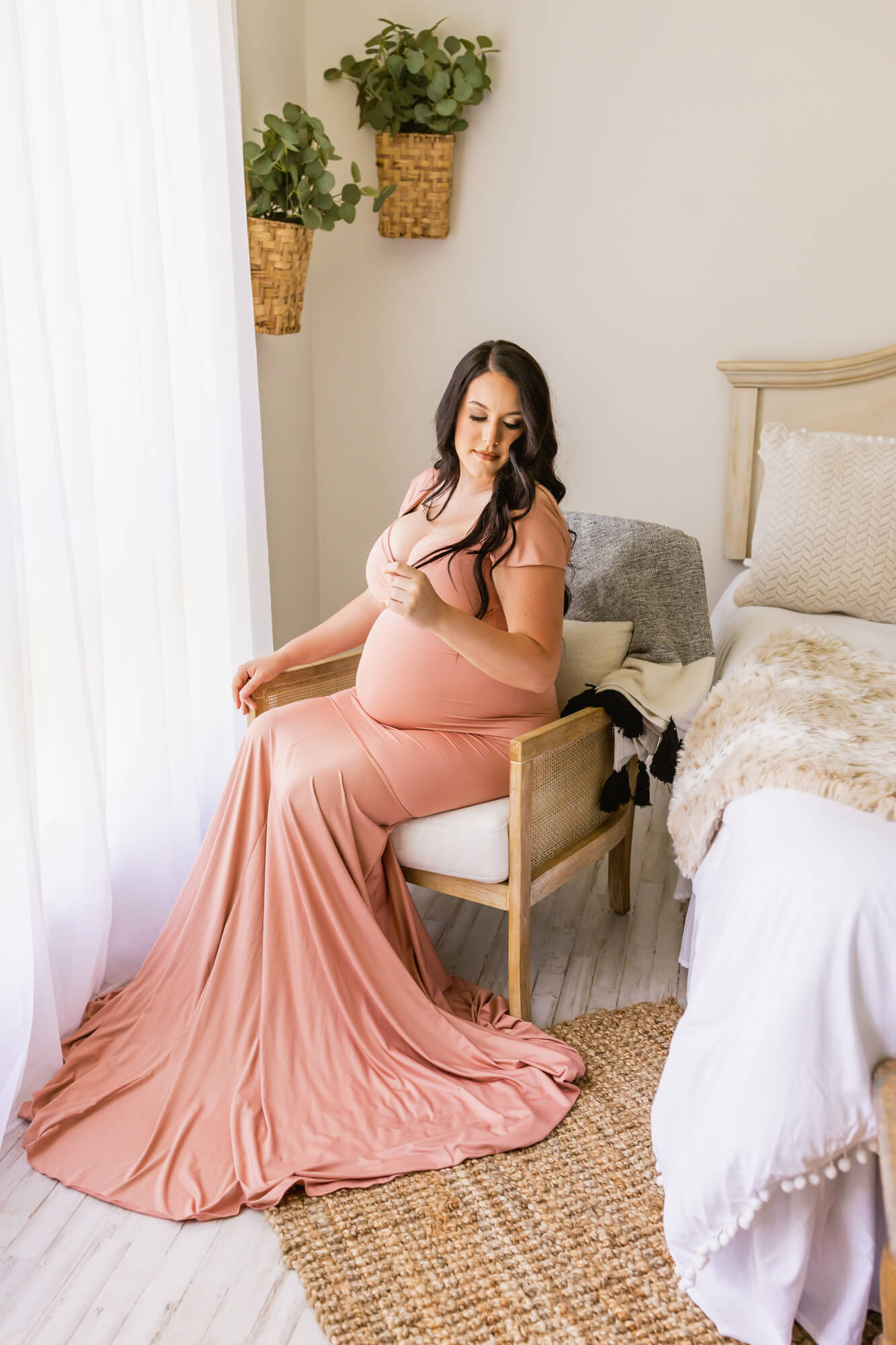 mom to be in pink maternity gown sitting in a chair in her bedroom Birthwell Partners
