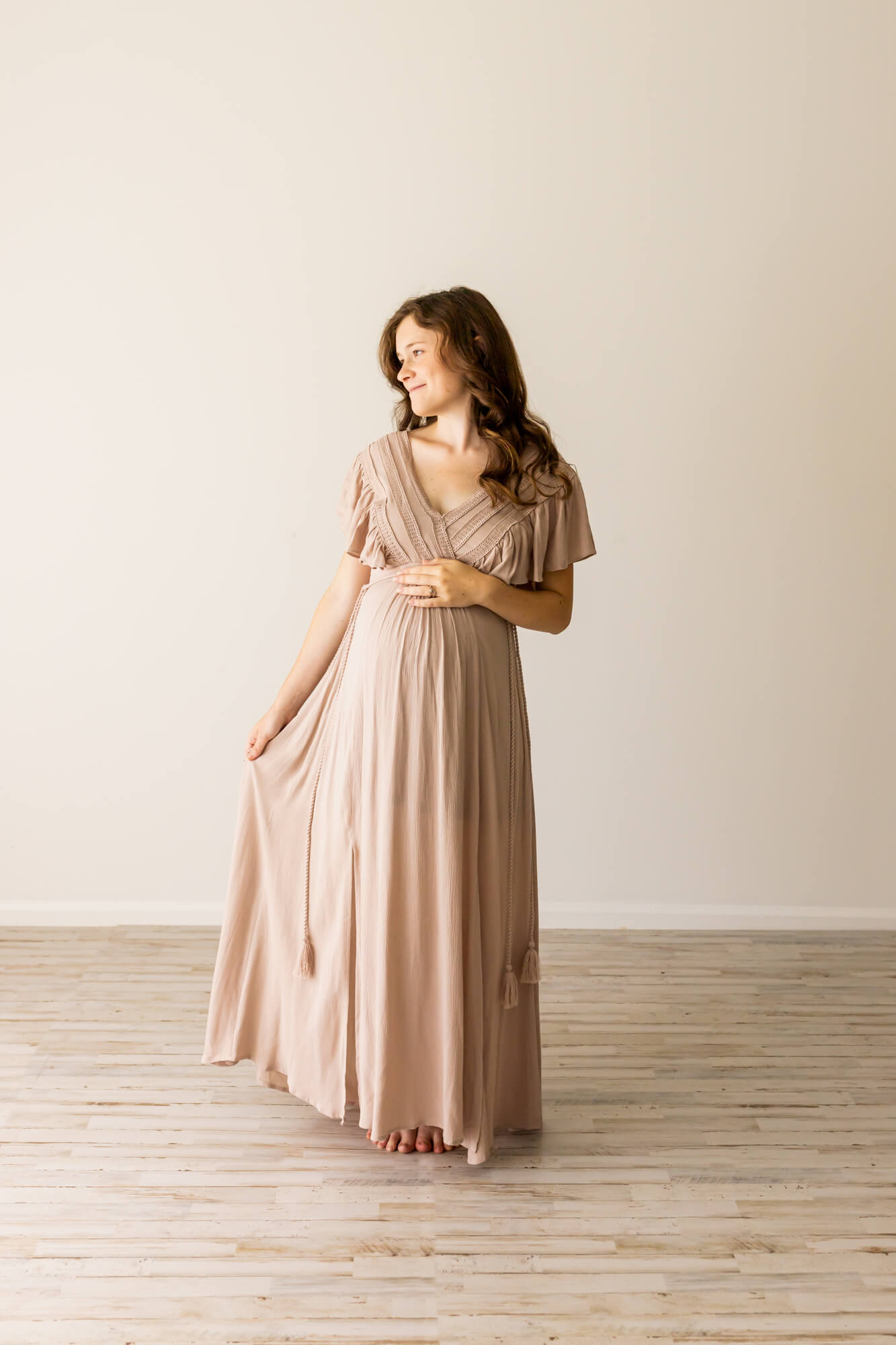 mom to be in neutral maternity gown looking out the window