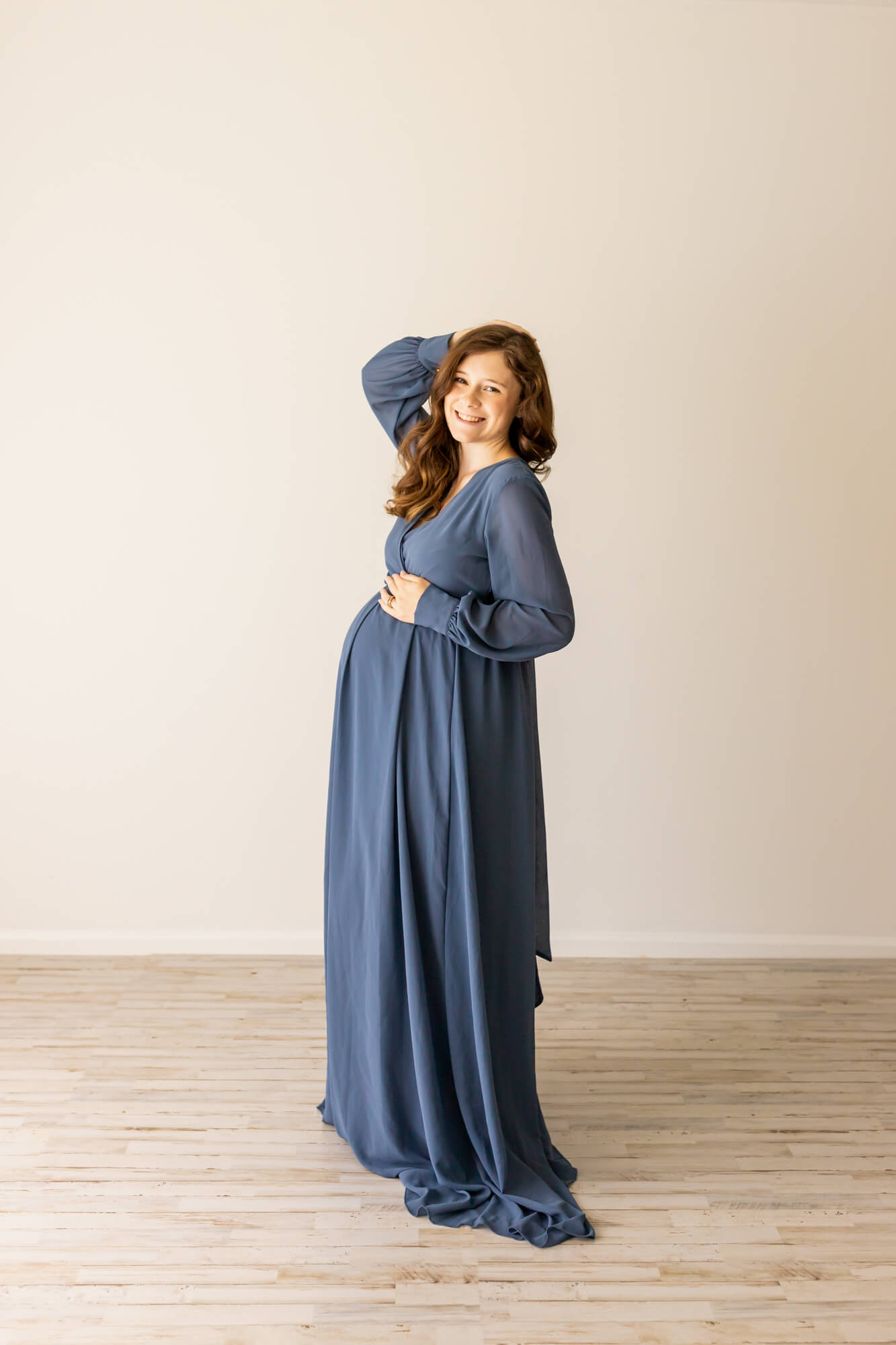 pregnant woman in blue gown with her hand on her bump and in her hair