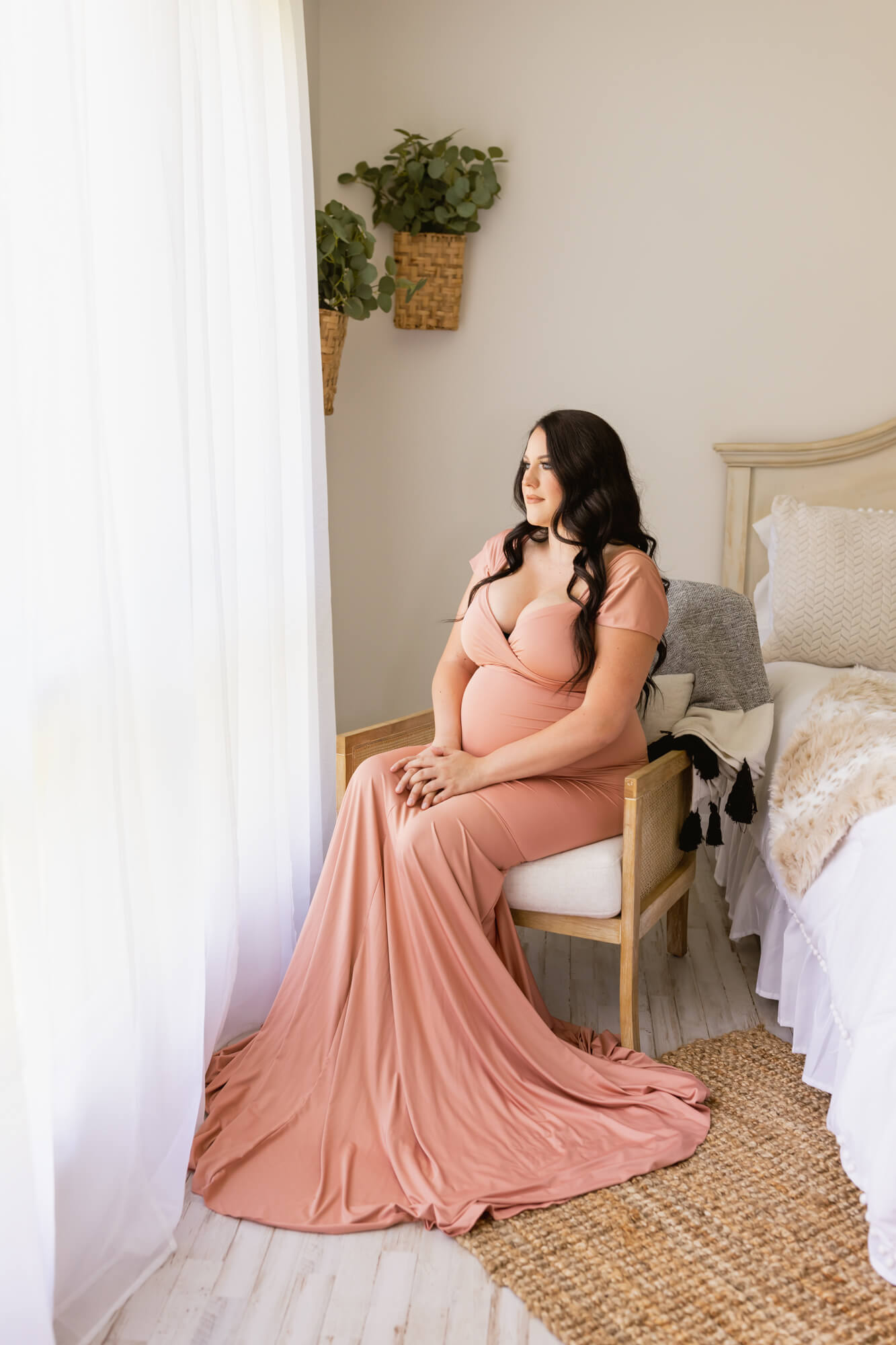 pregnant woman in pink gown with a train sitting by the window