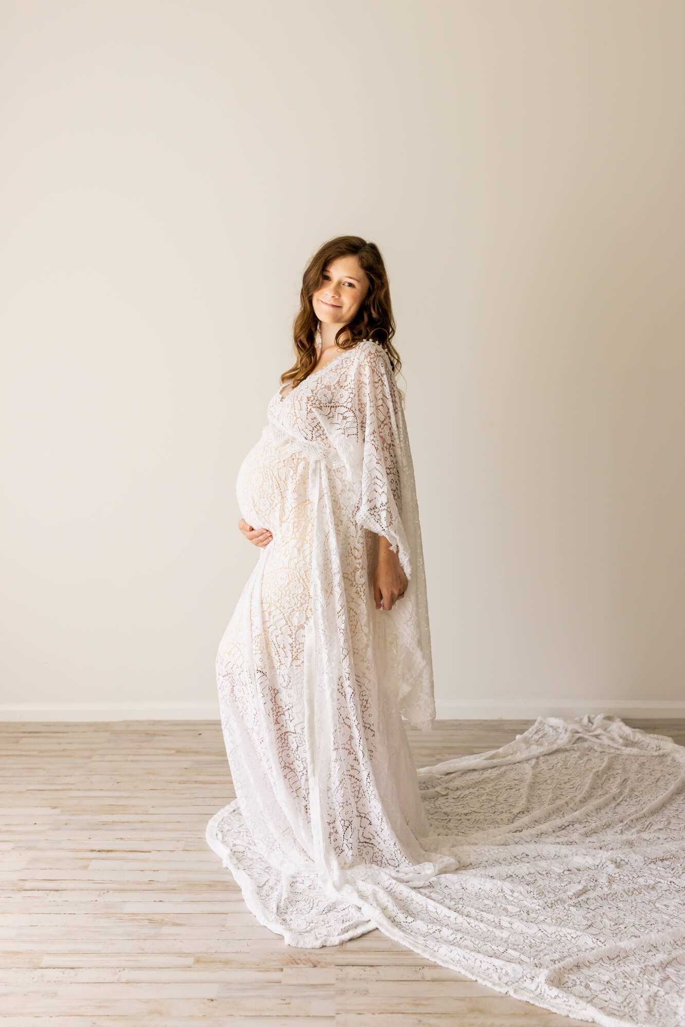 pregnant woman in white lace maternity gown holding her bump Birthwise Birmingham