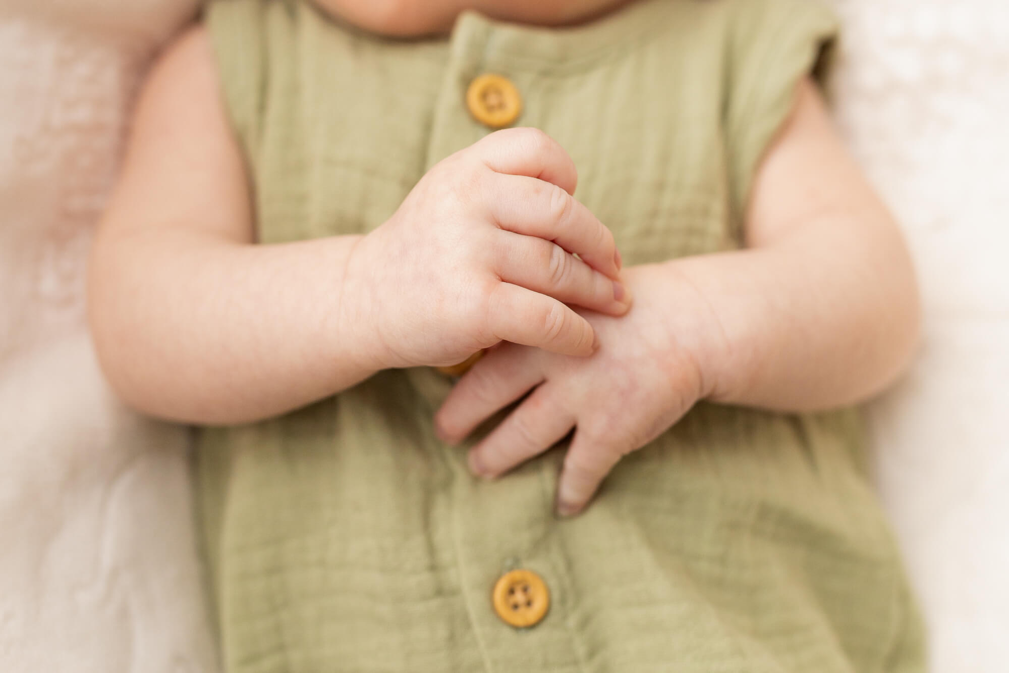 close up details of a young baby's hands on their onesie