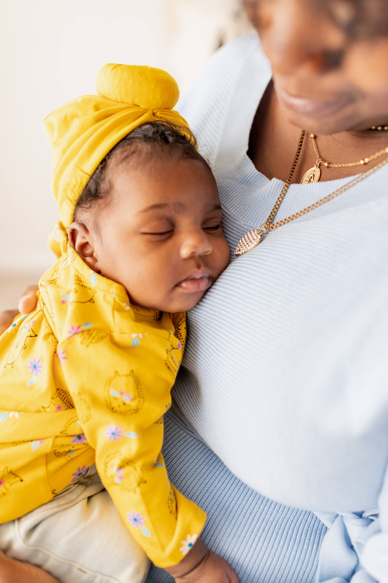 newborn baby girl dressed in yellow sleeping on her mom's chest UAB Maternal Fetal Medicine