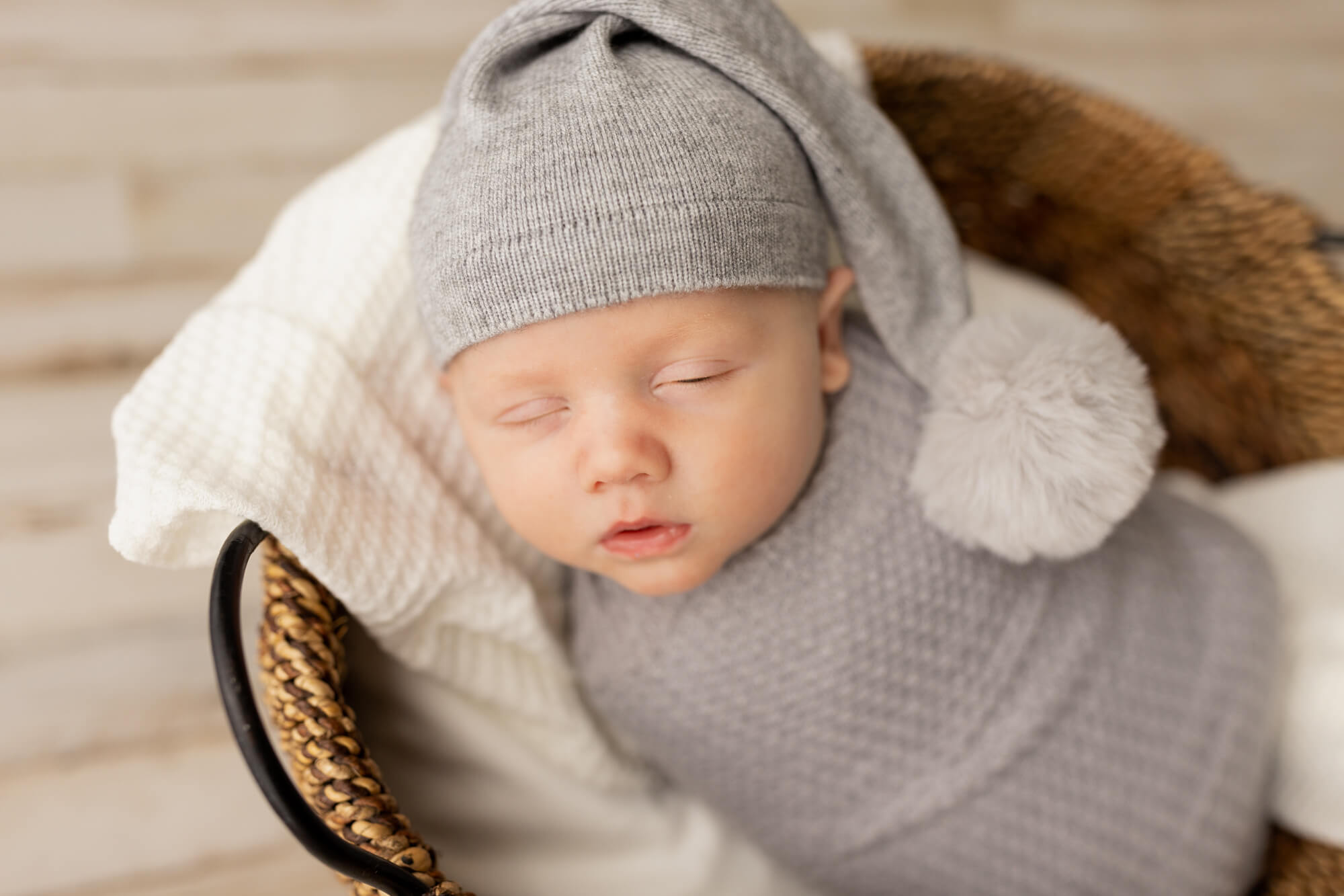 newborn baby in grey wrap and cap sleeping in a basket UAB Women & Infants Center