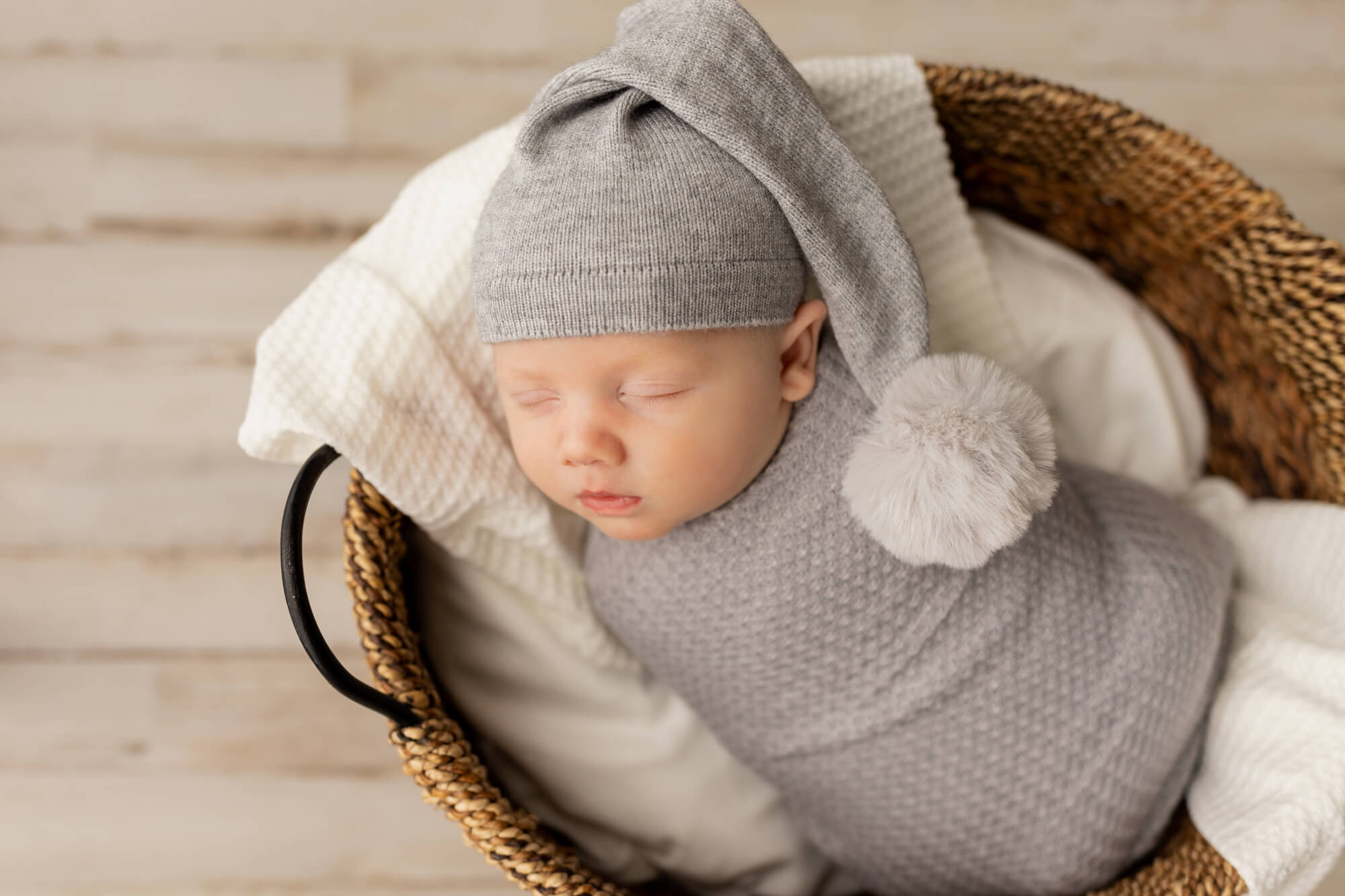newborn in grey wrap and hat sleeping