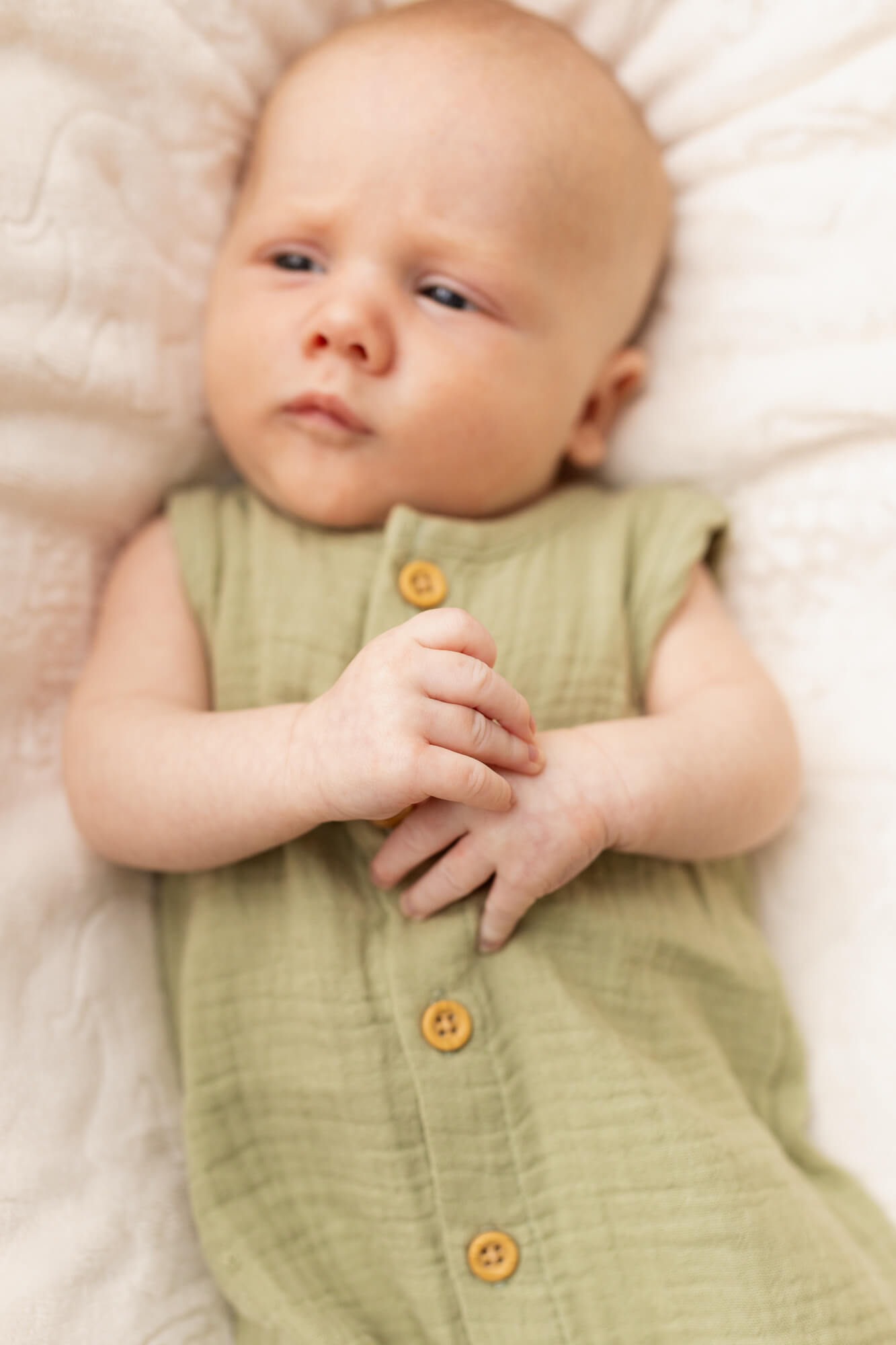 newborn baby boy in green onesie with his arms on his chest infant swim lessons birmingham al