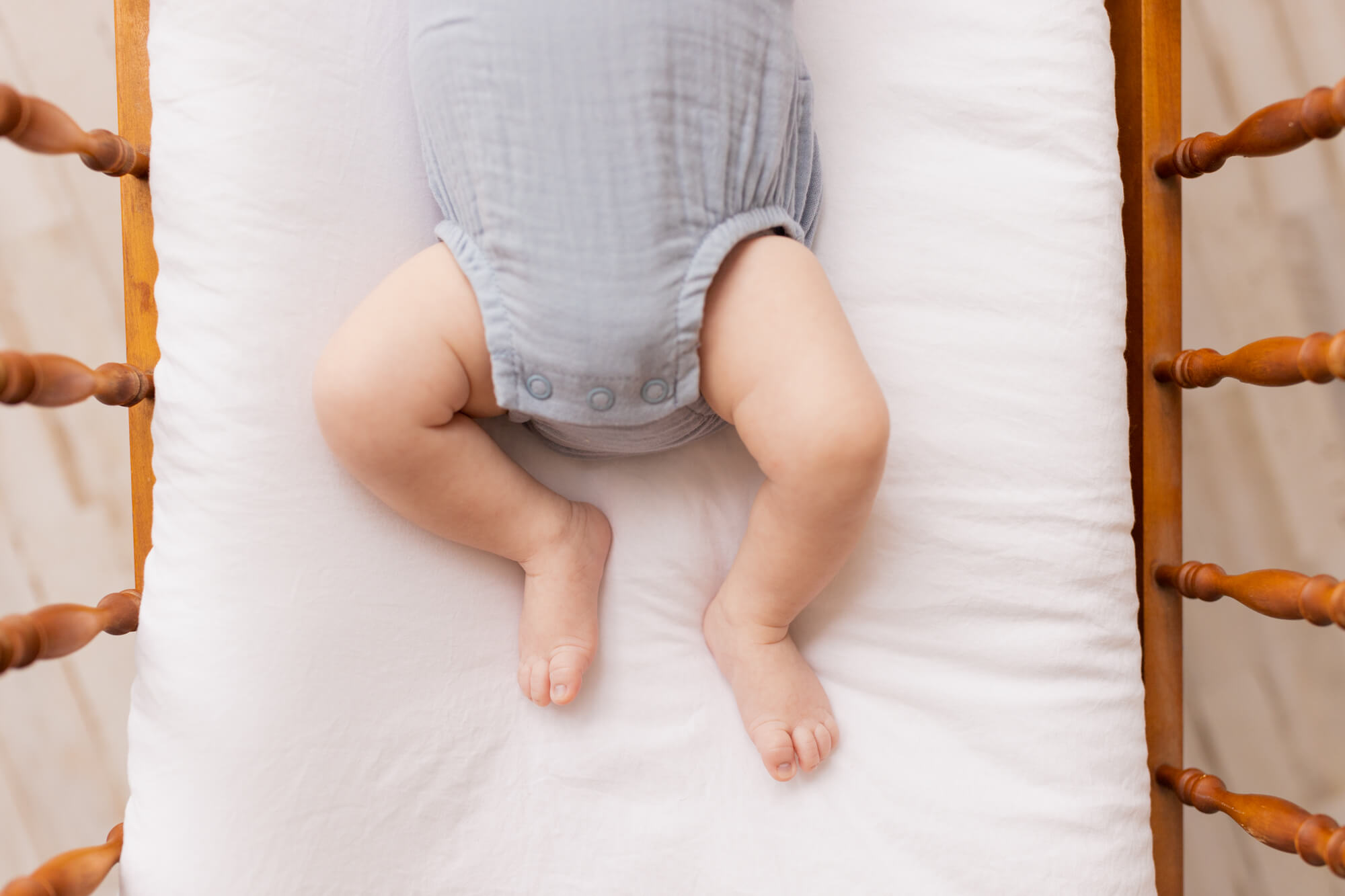 newborn baby's legs in blue onesie laying in a crib Cloth Diaper Service Birmingham Al