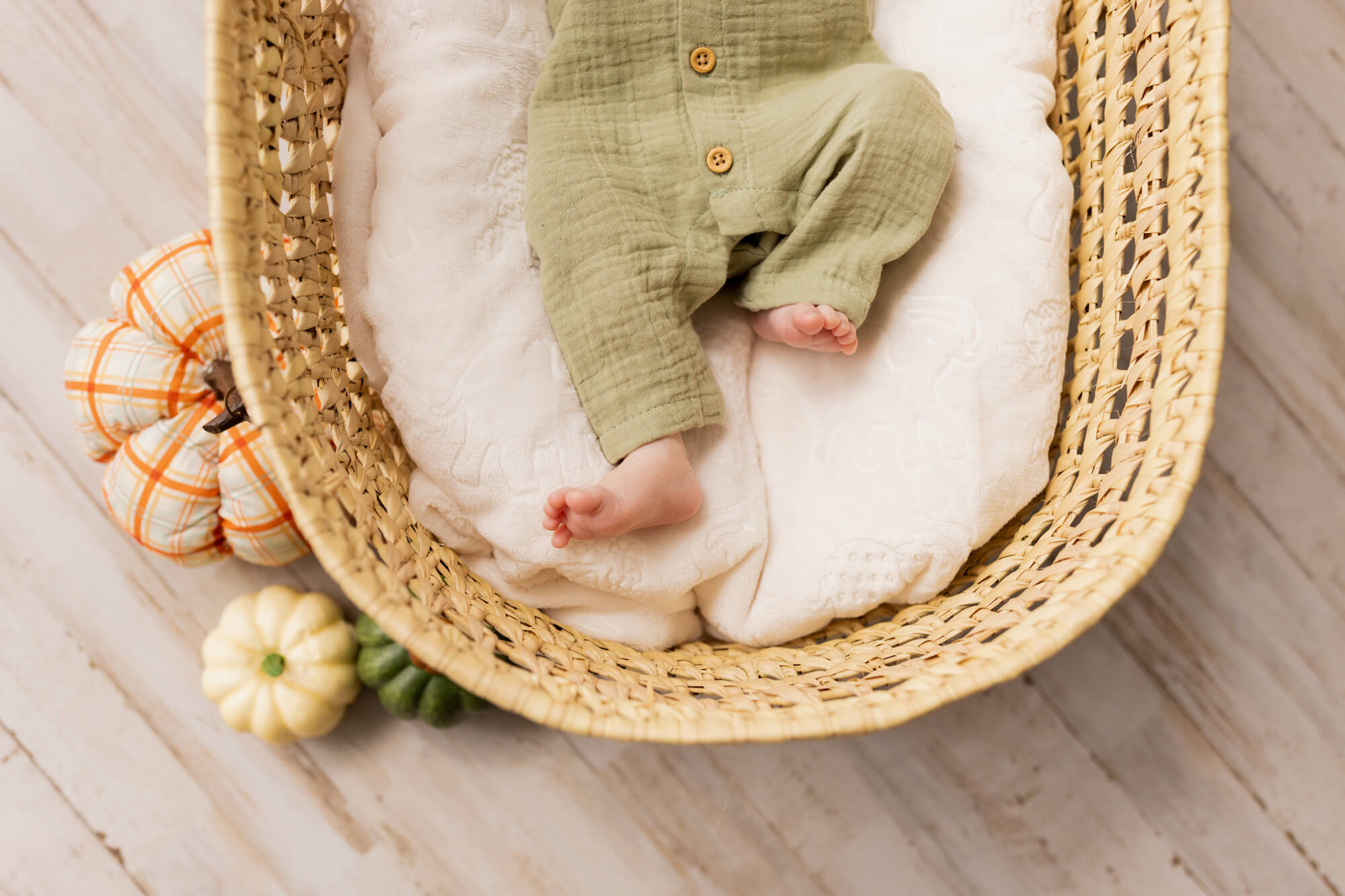 newborn baby in green outfit in a basket