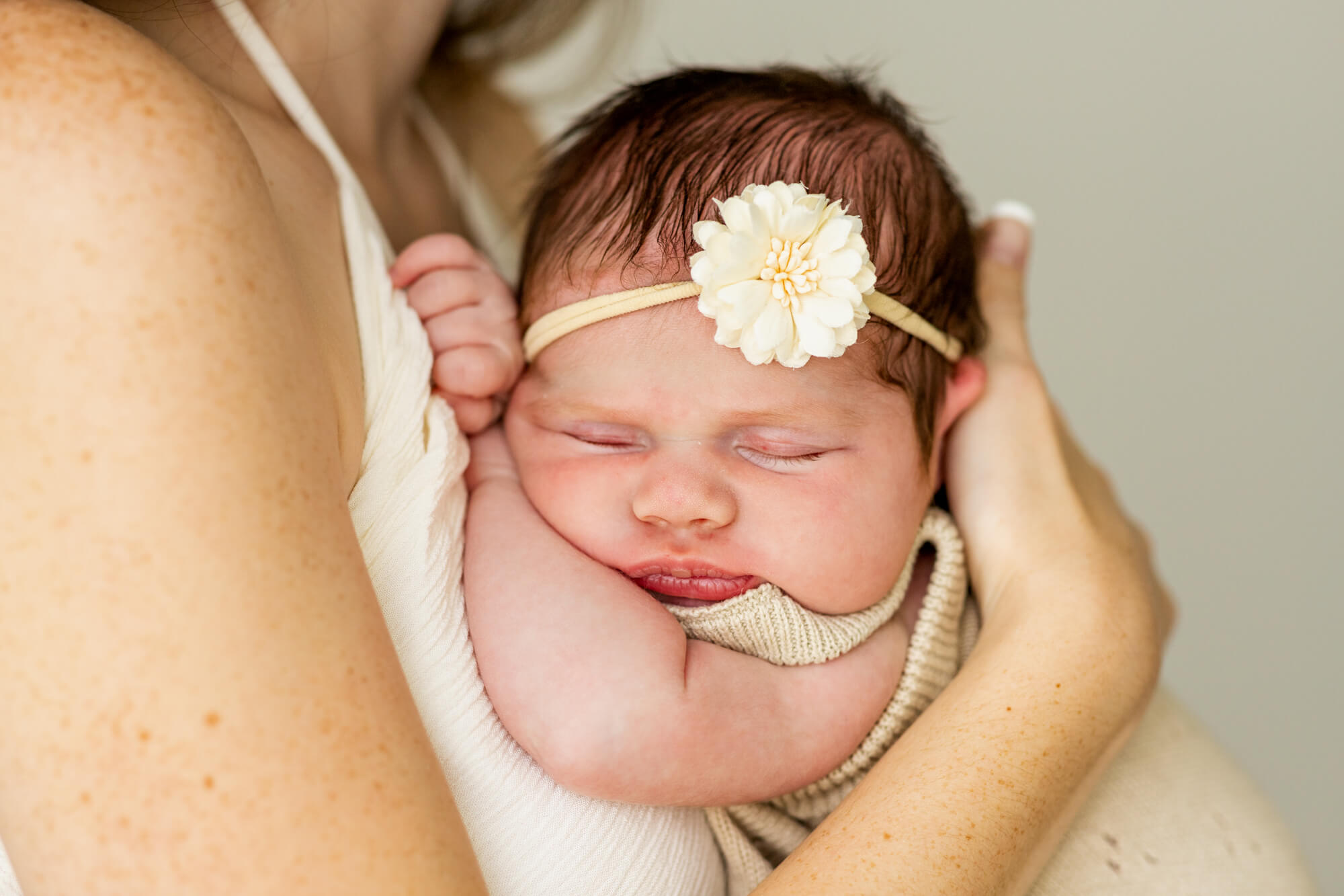 newborn baby girl with a daisy headband sleeping on her mom The Lili Pad Birmingham AL