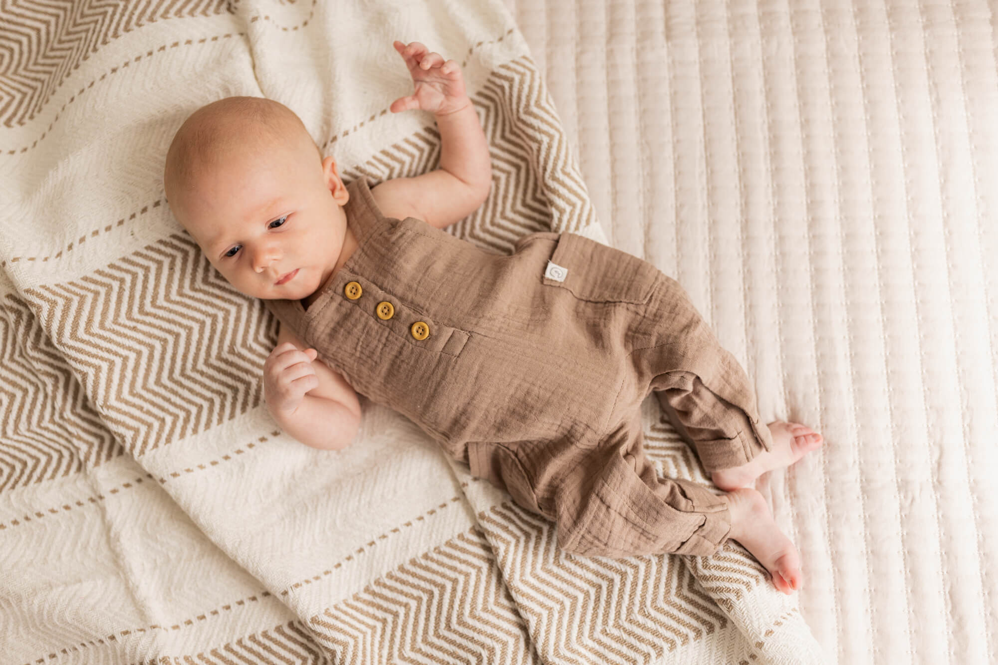 baby in brown onesie laying on his back storkland baby