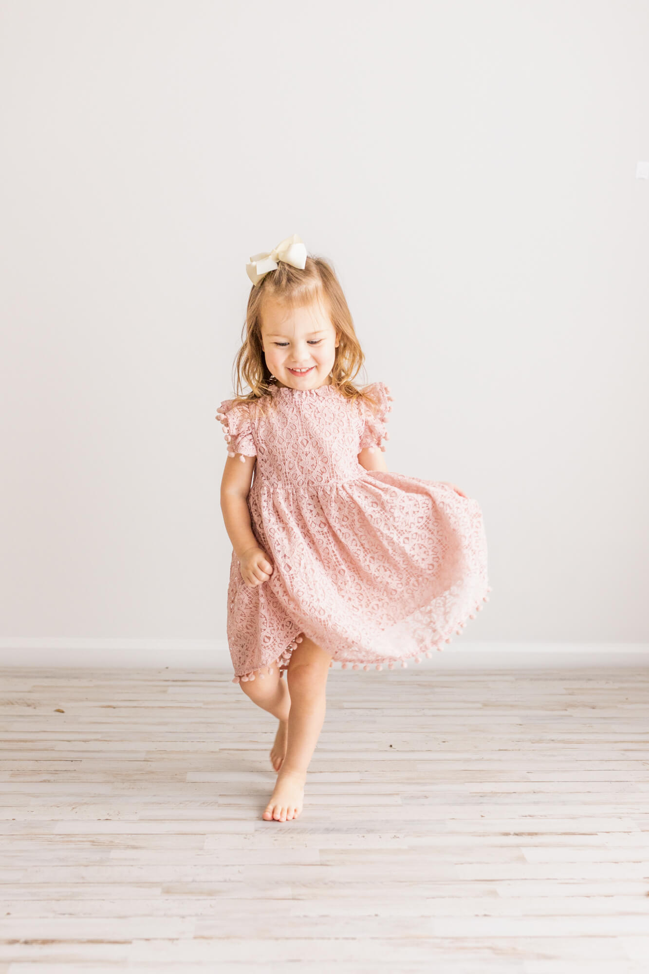 young girl walks and plays with her pink dress in a studio birmingham babysitters