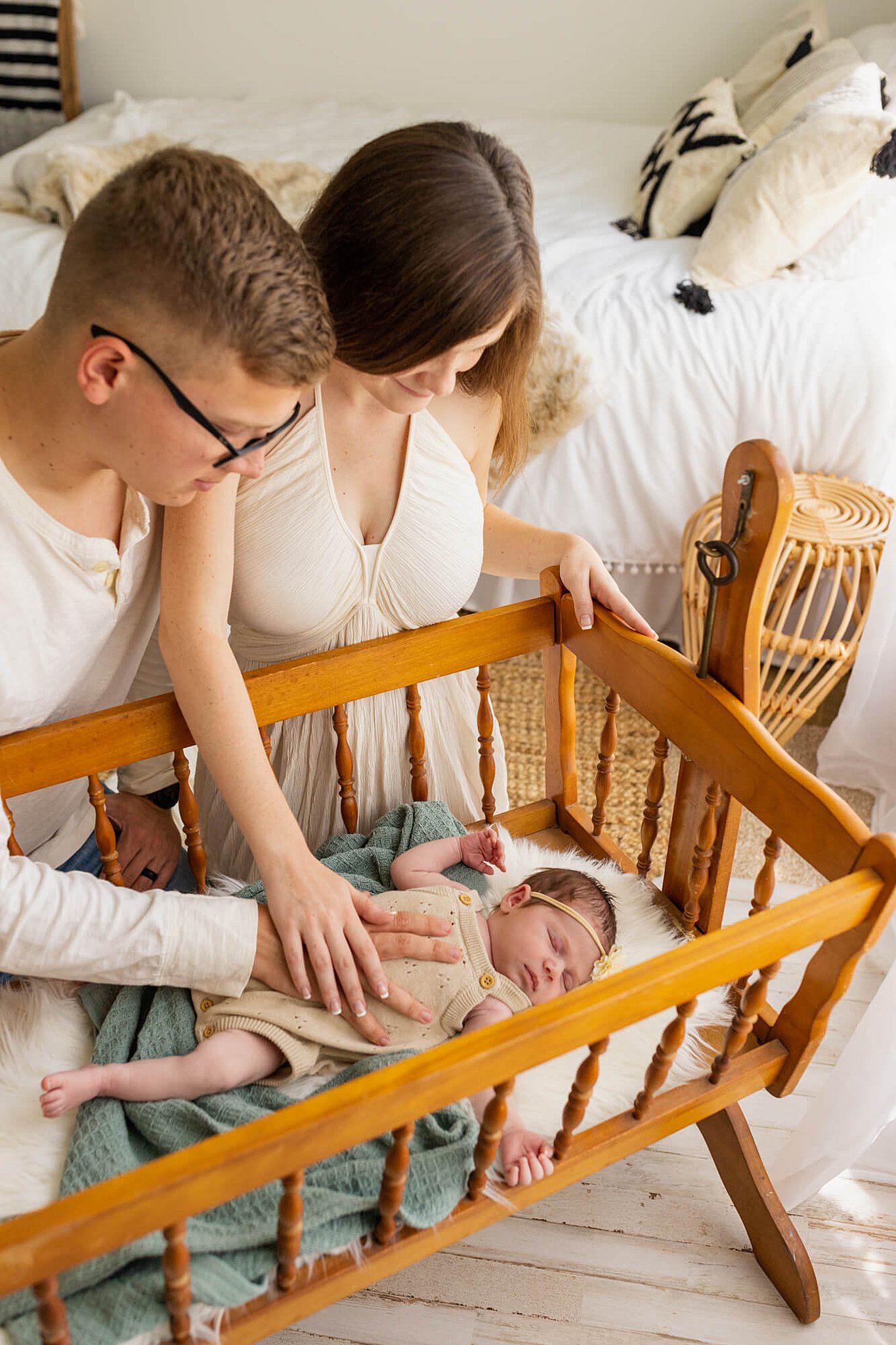 mom and dad with their hands on their baby looking into his crib interior designer birmingham