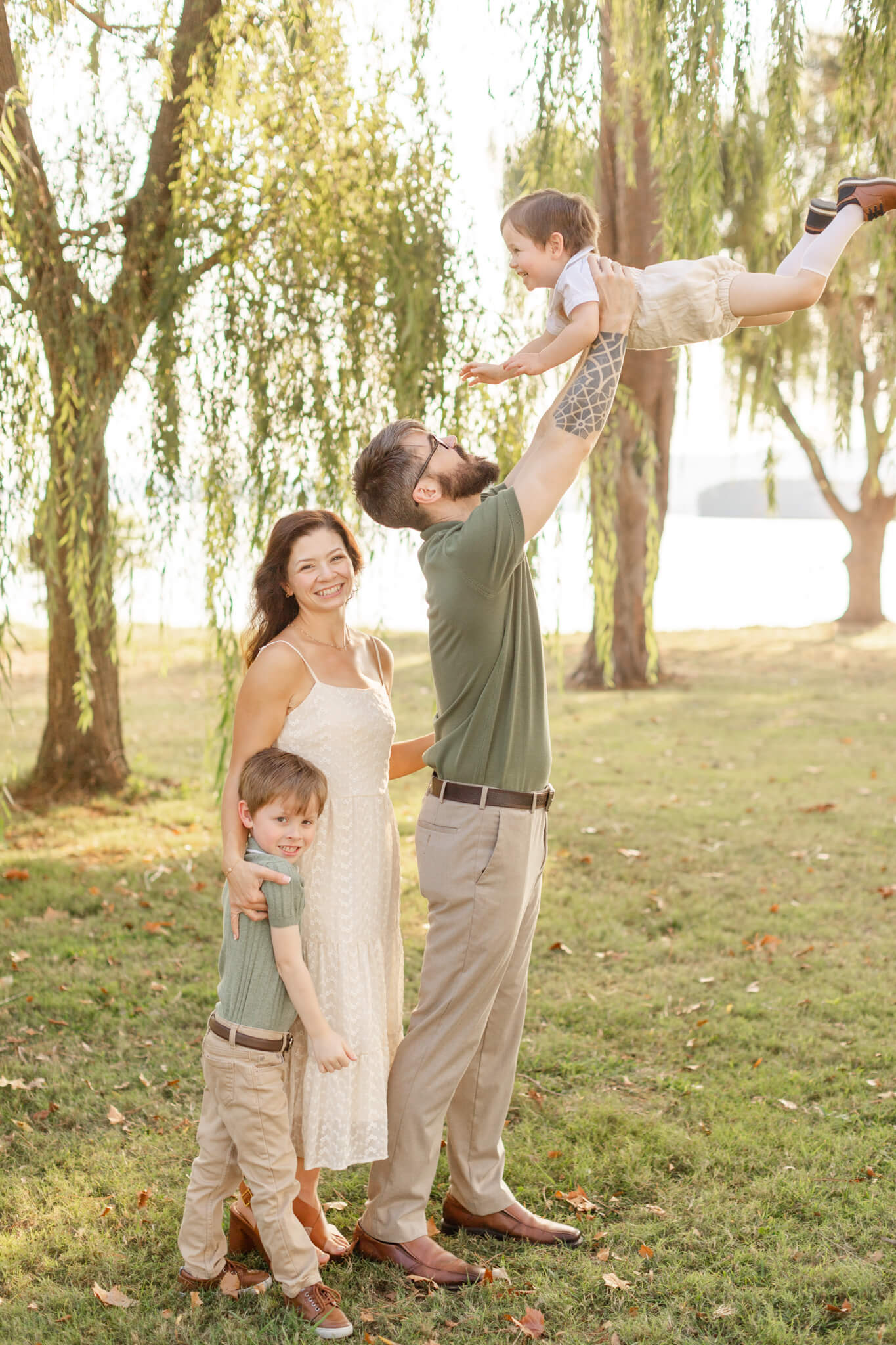A mom smiles while standing with her toddler son and husband tossing up their other toddler after visiting daycares in huntsville al