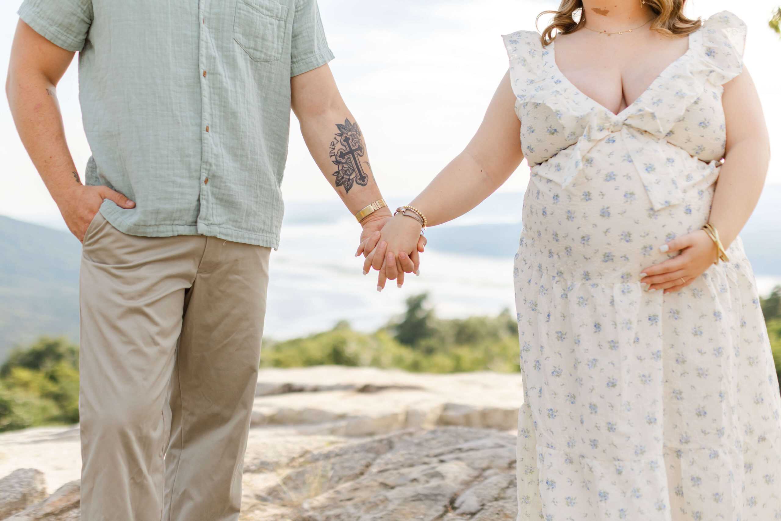 Details of a pregnant couple walking holding hands on a mountain hike
