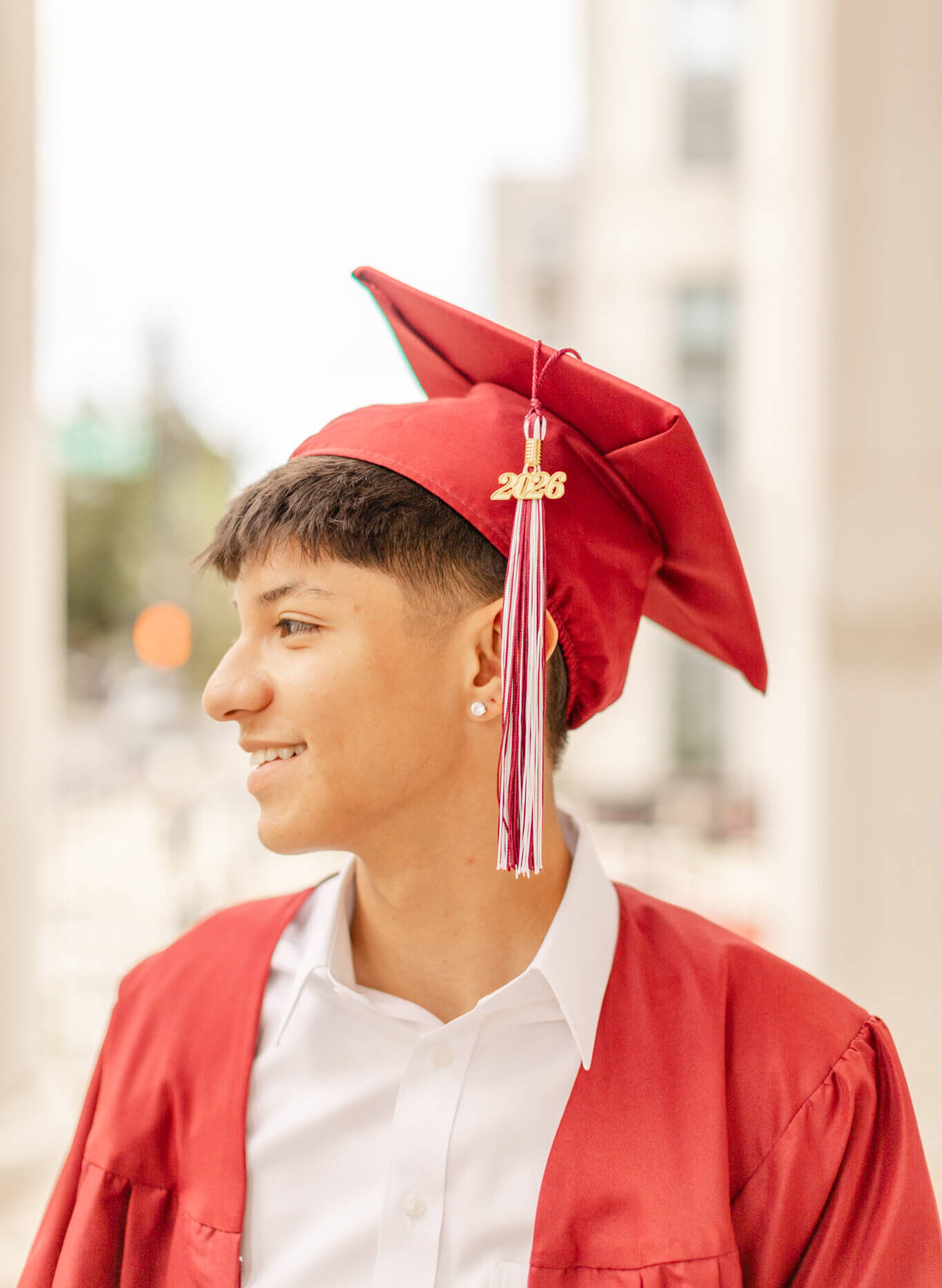 A high school grad in red cap and gown smiles after exploring colleges near huntsville al
